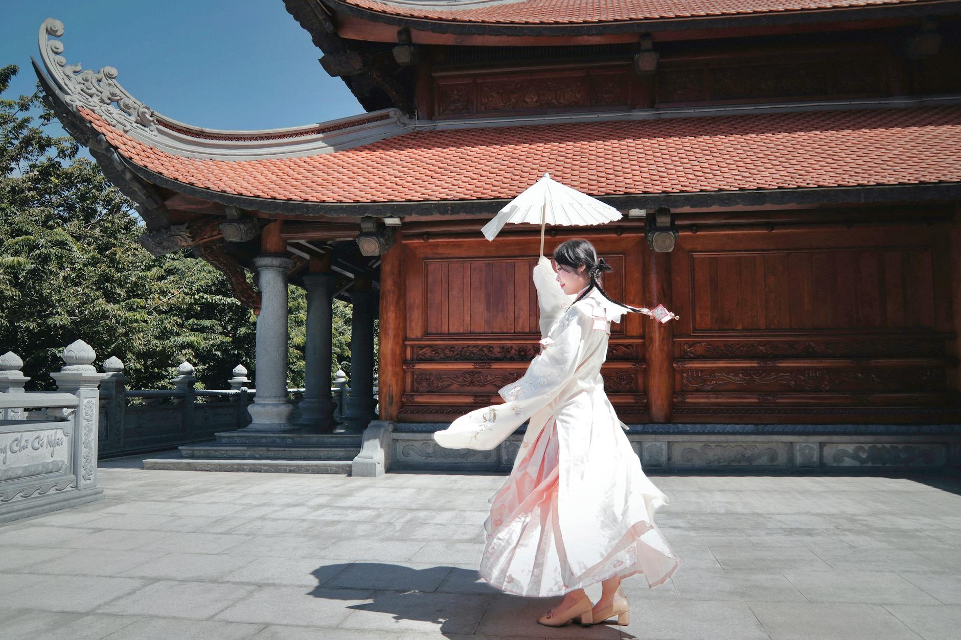 Kobieta w tradycyjnym stroju z parasolką przy azjatyckiej świątyni