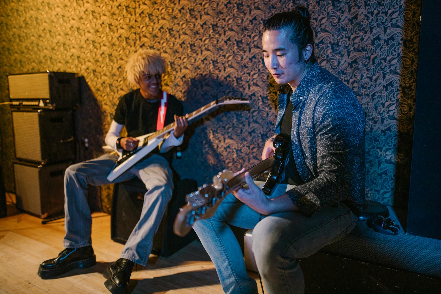 Niespodziewane duety: kto z kim nagrał nowy utwór? Dwóch muzyków gra na gitarze i basie w przytulnej sali prób