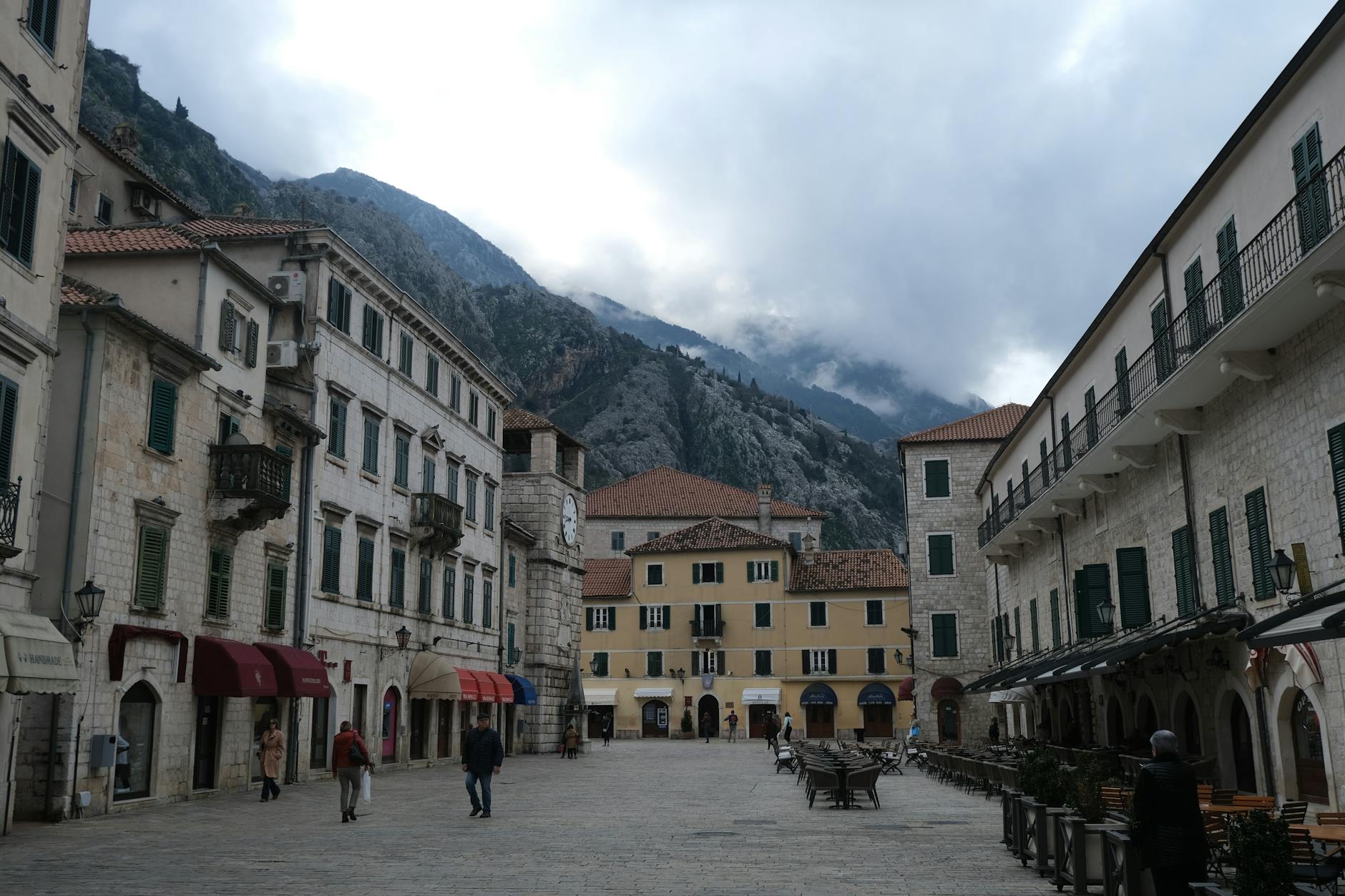 Średniowieczny rynek w Kotorze z górami w tle, cel taniej podróży po Bałkanach