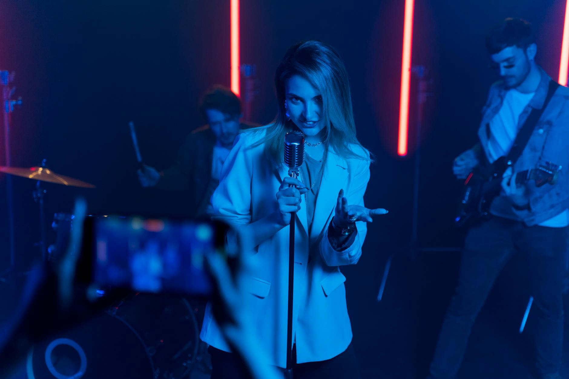 Wokalistka z mikrofonem na scenie z kolorowymi światłami