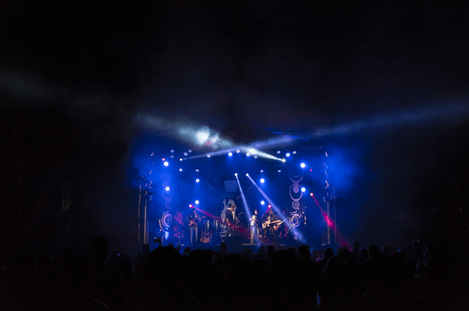 Zespół rockowy na scenie w kolorowych światłach przed żywiołową publicznością